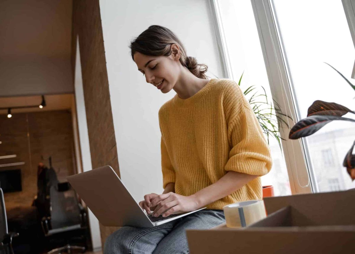 Office worker uses laptop near moving box